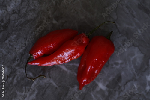 Foto Fresh red Peruvian aji limo chili peppers on a dark stone surface