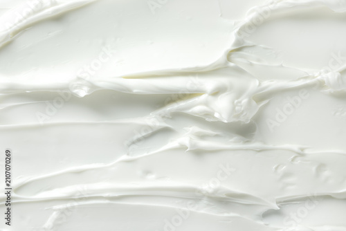 White cosmetic cream texture with glossy swirls and peaks. Smooth whipped moisturizer background for skincare design and beauty branding.