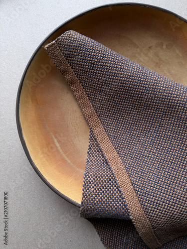 Brown linen napkin on a black ceramic plate in a minimalist composition. Natural textile texture and handmade stoneware create a calm aesthetic for home decor, dining and lifestyle projects.