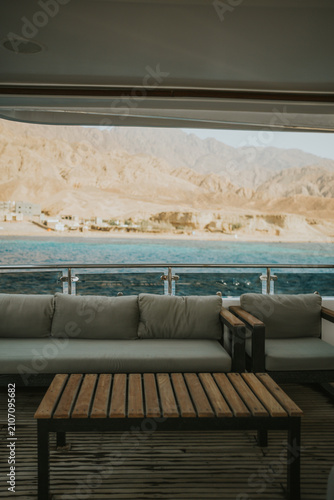 Yacht interior with lounge seating overlooking desert mountains and blue water