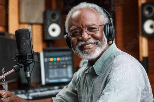 Grandpa records a podcast in a studio with a microphone and headphones on a weekday afternoon