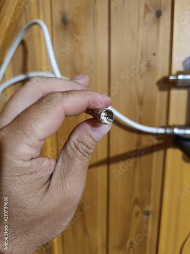 Cuadro en lienzo Hand holding a white coaxial cable with a metallic F-type connector