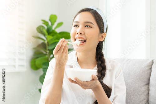Healthy lifestyle, wellness food asian young woman hand use spoon eat tasty fresh organic yogurt, dairy product in bowl breakfast meal at home. Snack tasty on diet nutrition delicious natural yoghurt