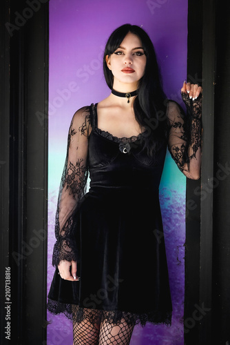 pretty goth girl wearing black dress in front of colorful glass window