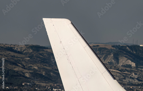 Close-up of airplane vertical stabilizer tail fin with mountains in the background