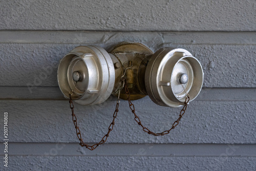 Siamese fire department connection on a textured gray wall