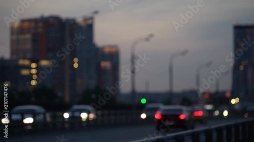 Blurred urban traffic with glowing car lights and city buildings at dusk, modern transportation scene showing mobility, movement and metropolitan lifestyle