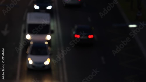 Blurred vehicles driving on city road at night with glowing headlights and taillights, abstract transportation scene showing urban mobility and motion