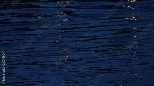 Dark blue water surface with natural wave patterns and subtle reflections, abstract aquatic texture background for design, nature and environmental projects