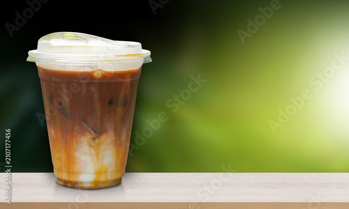 front view ice coffee in a plastic cup, placed on a wooden floor, blur green wall background, drink, food, object, decor, copy space