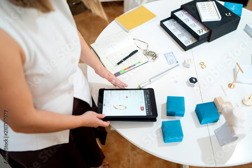 Artisan creating and organizing handmade jewelry for online business on a tablet
