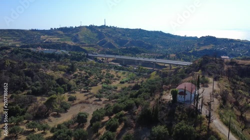 Aerial panoramic orbit shot of countryside chapel and distant bridge