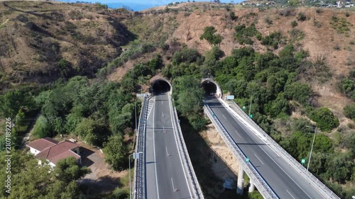 Aerial top-down view of straight highway overpass into twin tunnel