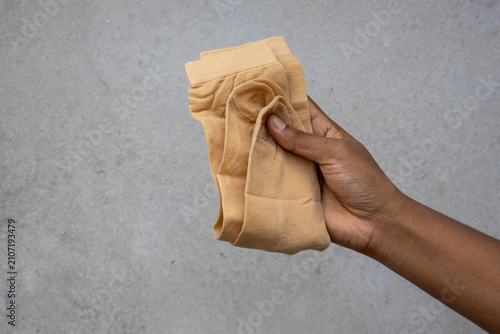 Photos Close-up female hand holding a pair of folded skin color socks