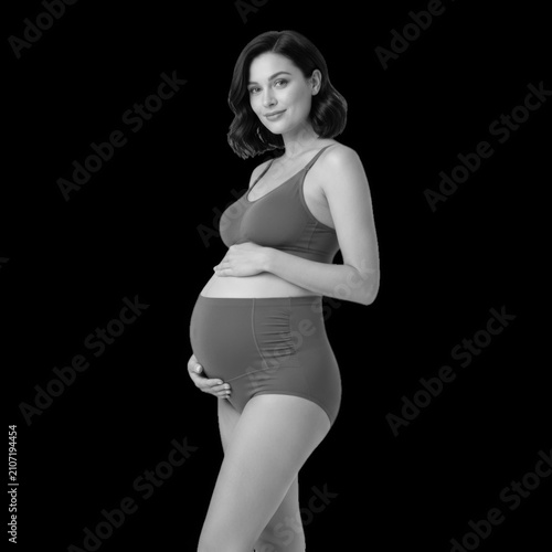 Beautiful pregnant woman smiling and holding her belly