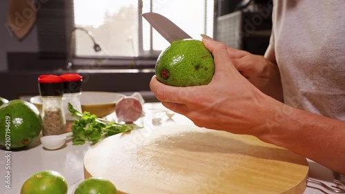 Woman Cuts Ripe Green Avocado with Kitchen Knife over Wooden Board, Healthy Food Preparation and Fresh Cooking