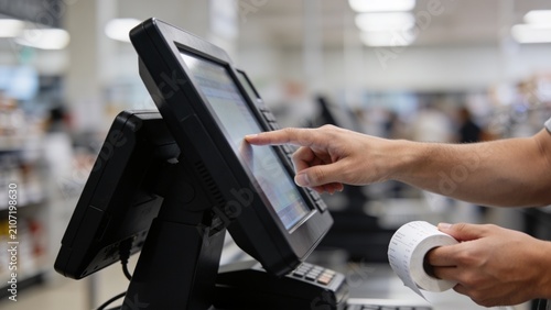 Person using self-checkout kiosk in modern supermarket with digital payment terminal