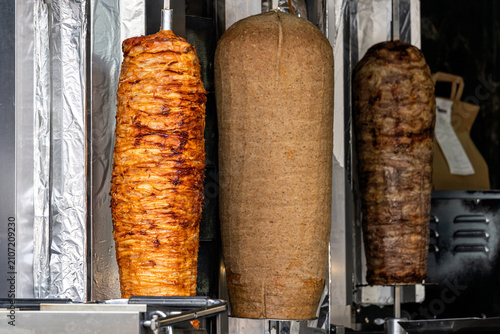 Konstfotografi vertical rotisserie spits loaded with layers of seasoned meat for döner kebab