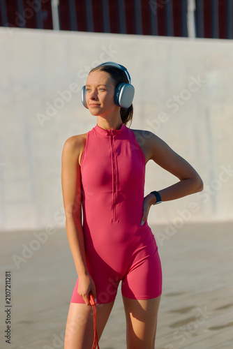 Sporty young woman enjoying sunny outdoor activity in vibrant pink outfit with headphones
