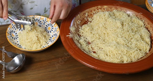 Serving Moroccan Seffa vermicelli into a small bowl with tongs and hands
