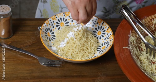 Garnishing traditional Moroccan Seffa vermicelli with icing sugar and cinnamon