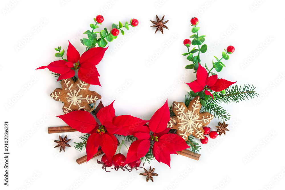 Fototapeta premium Christmas decoration with red poinsettia, gingerbread cookie, and winter spices on white background with space for text. Flat lay, top view