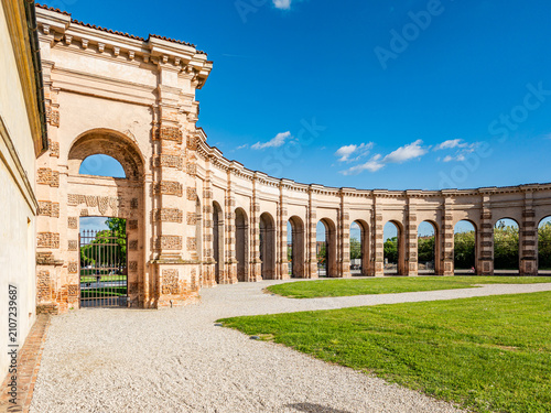 Palazzo Te creating a curved Renaissance colonnade in Mantova, Italy, offering a view of historical architecture and beautiful surrounding gardens under a clear sky