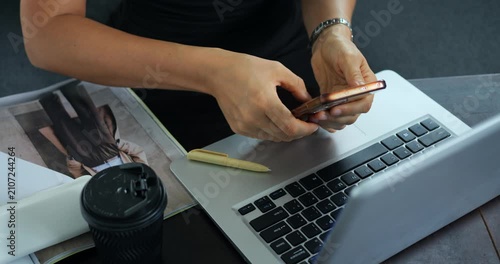 Relaxing while multitasking on electronic devices. Quick engagement with phone and computer during short break. Person simultaneously using mobile and laptop during relaxed interval of work