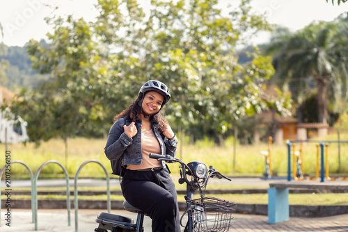 Confident young Black woman adjusting her backpack while sitting on her electric bicycle, representing an active, sustainable lifestyle.