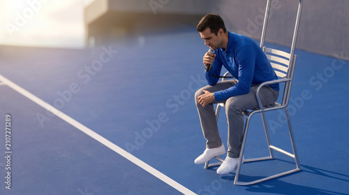 Tennis umpire sitting in high chair on blue tennis court  