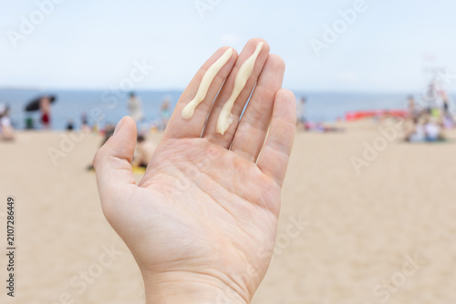 Closeup of a man applying the correct amount of sunscreen for face and neck on a beach. 