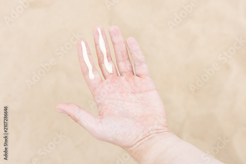 Closeup of a man applying the correct amount of sunscreen for face and neck on a beach. 