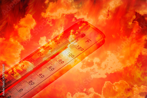 Thermometer showing high temperature against fiery hot sky, symbolizing climate change and heatwave.