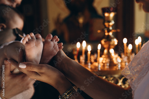 Photos Close-up of a mother gently holding her baby's tiny feet during a Christian baptism ceremony in church