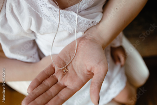 Photos Close-up of a baptism cross resting in a person's hand during a Christian baptism ceremony