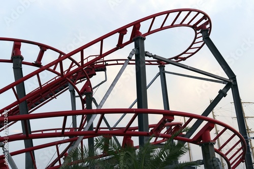 Red roller coaster tracks against a bright sky