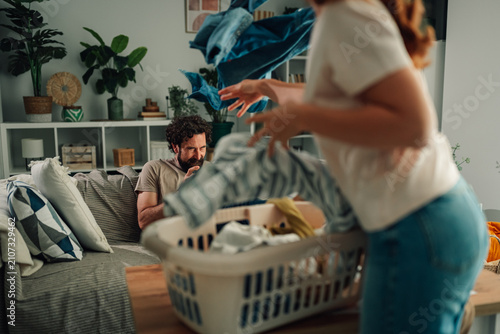 Photography Couple arguing about housework at home, wife throwing dirty laundry from basket