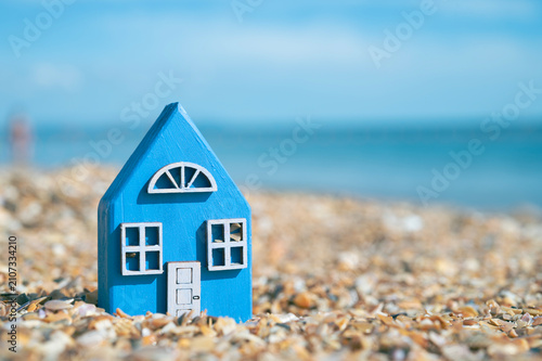 A colorful wooden toy house against the backdrop of the seashore and ocean. Seaside house concept.