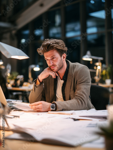 Young adult man working overtime late at night