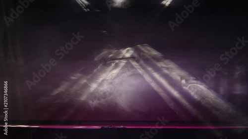 The stage of the night club illuminated by spotlights and smoke