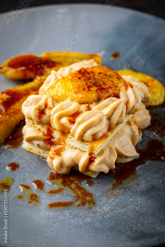 Dessert puff pastry layered mille-feuille with pastry cream and caramelized banana with butter caramel sauce served as close-up on a design plate