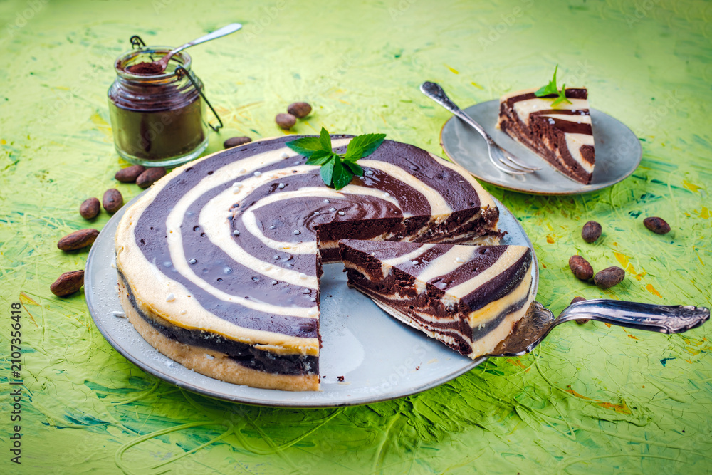 Obraz premium Artisan homemade baked zebra black-white cheesecake pie with dark chocolate served as close-up on a cake plate
