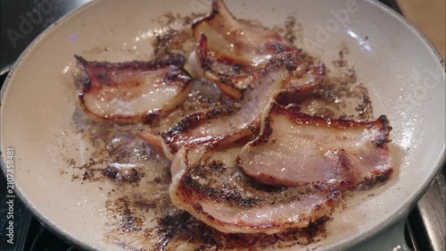 Thick cut bacon frying in a hot pan