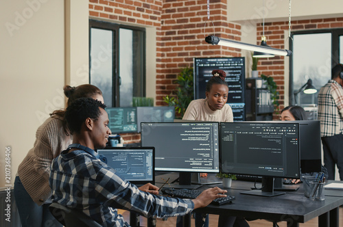 Obraz na płótnie Programmer analyzing compiling code on multiple screens takes off glasses and doing high five hand gesture with colleague developer, software developers celebrating successful coding