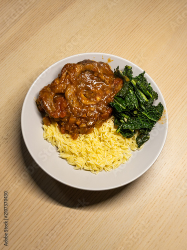 Foto A plate of osso buco with kale and orzo.