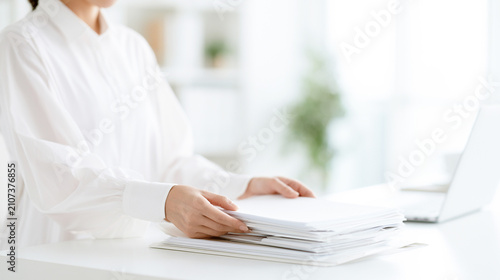 明るいオフィスで書類を整理する女性会社員の手元
