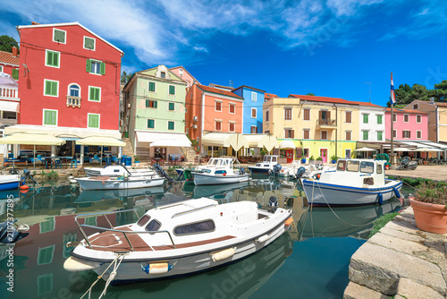 Colorful waterfront of Mali Losinj on Losinj Island,Croatia. Historic harbor with fishing boats, pastel buildings and Adriatic Sea under blue summer sky in Kvarner Bay on Adriatic coast in Kvarner Bay