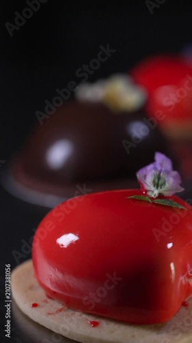 Close up of an elegant red mousse pastry featuring a beautiful shiny mirror glaze, delicately decorated with a small lavender flower, professional confectionery, cinematic food videography
