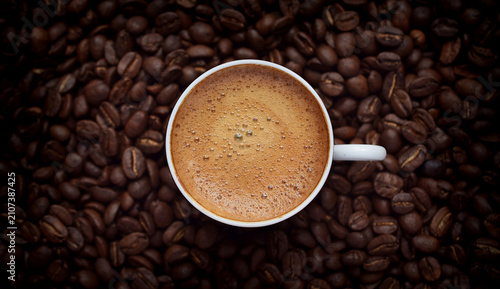 фотографія Fresh espresso in a white cup resting on roasted coffee beans, premium beverage