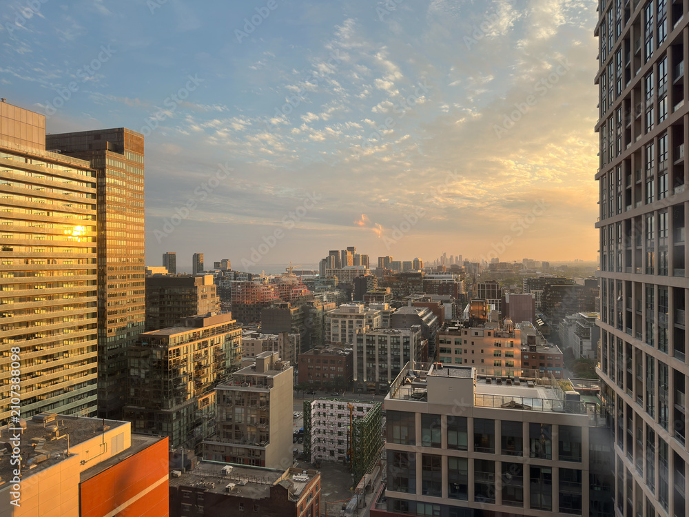 Obraz premium Toronto city skyline is displaying a mix of modern and historical architecture, with office towers and residential buildings in the evening sunset